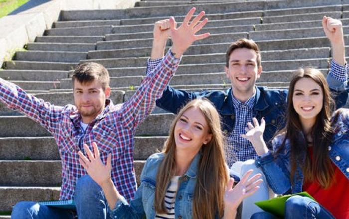 immagine di studenti che salutano sorridenti seduti sui gradini di una scalinata